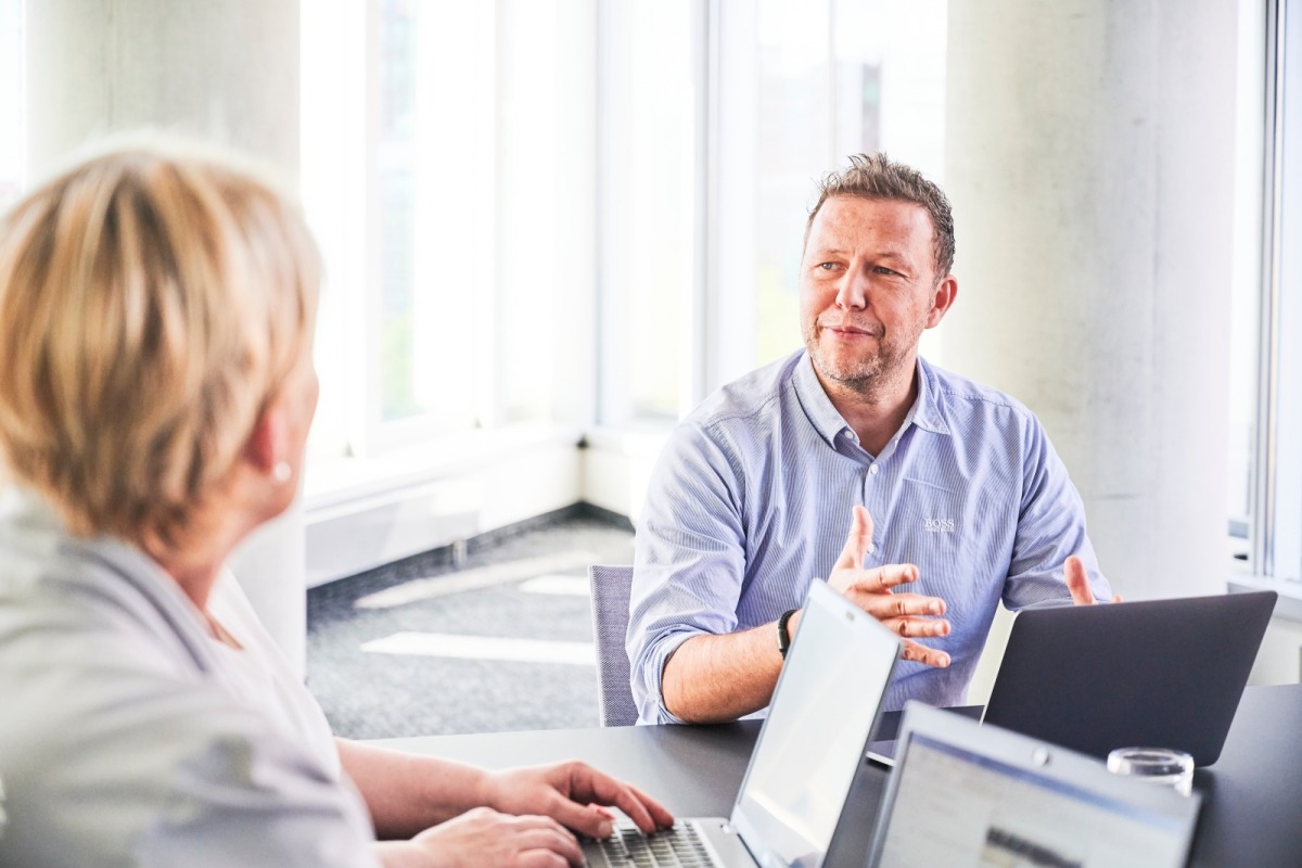 Mann und Frau mit Laptops an einem Konferenz Tisch