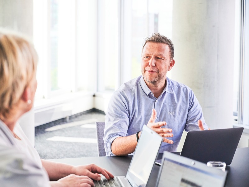 Mann und Frau mit Laptops an einem Konferenz Tisch